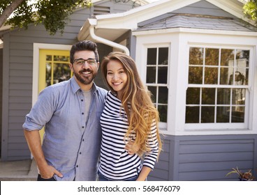 Portrait Of Excited Couple Standing Outside New Home