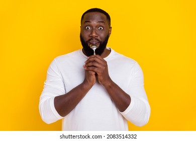 Portrait Of Excited Crazy Guy Hold Lick Spoon Have Good Mood Look Camera Isolated On Yellow Color Background