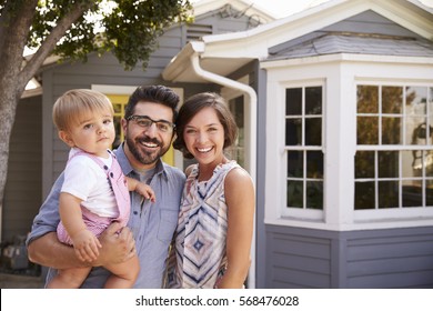 Portrait Of Excited Family Standing Outside New Home