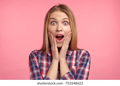 Portrait Of Excited Female Model Has Appealing Appearace Stares At Camera With Unbelievable Gaze, Suprised To Recieve Unexcpected Gift From Relatives. People, Facial Expressions, Emotions Concept