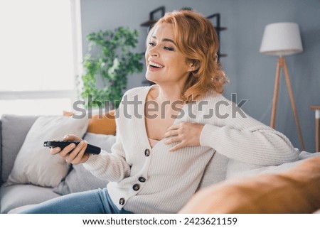 Portrait of excited funky person sit comfy sofa hold remote control watch tv laugh enjoy weekend flat inside