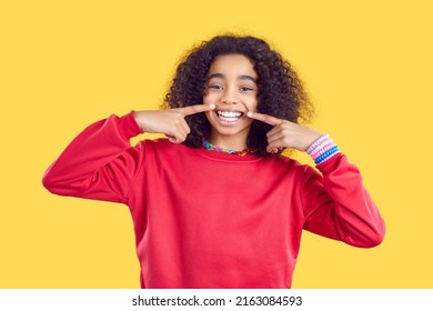 Portrait of excited funny African American teen girl in casual wear isolated on yellow studio background show smile. Overjoyed biracial kid feel joyful and optimistic share positivity and happiness. - Shutterstock ID 2163084593