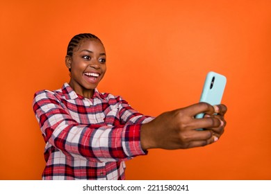 Portrait of excited funny person hold telephone make selfie record video isolated on orange color background