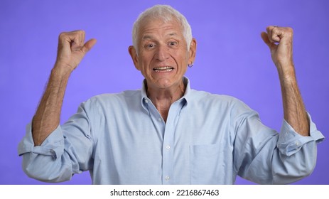 Portrait Of Excited Jubilant Overjoyed Elderly Man 70s Doing Winner Gesture Celebrate Clenching Fists Say Yes Isolated On Solid Purple Background Studio