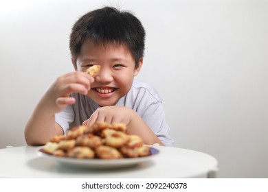 Portrait of an excited little Asian boy with a big stack of chocolate chip cookies, wide eyes and a huge smile as he smells the delicious cookies