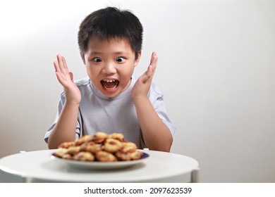 Portrait Of An Excited Little Asian Boy With A Big Stack Of Chocolate Chip Cookies, Wide Eyes And A Huge Smile As He Smells The Delicious Cookies