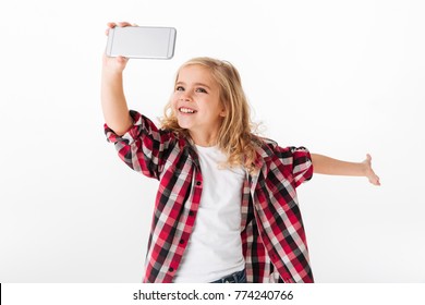 Portrait Of An Excited Little Girl Taking A Selfie Isolated Over White Background