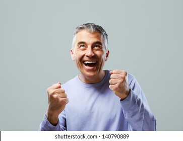 Portrait Of Excited Mature Man, Raising His Fists On Grey Background.