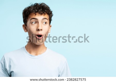 Portrait of excited positive teenage boy looking away isolated on blue background. Concept of shopping, discounts, sales, advertisement
