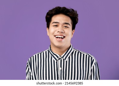 Portrait of excited young Asian male laughing wearing casual striped shirt posing standing isolated over purple violet studio background. Happy adult person smiling looking at camera with open mouth - Powered by Shutterstock