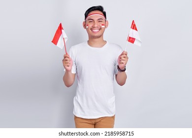 Portrait Of Excited Young Asian Man Celebrating Indonesian Independence Day On 17 August And Holding Indonesian Flag Isolated On White Background Studio Portrait