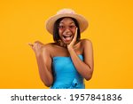 Portrait of excited young black woman in trendy outfit screaming WOW and pointing aside on orange studio background. Unbelievable summer sale, promo, discount concept