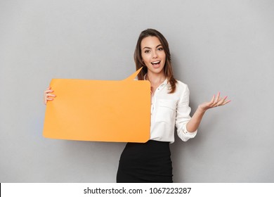 Portrait Of An Excited Young Business Woman Holding Empty Speech Bubble Isolated Over White Background