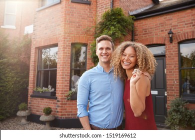 Portrait Of Excited Young Couple Standing Outside New Home Together