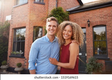 Portrait Of Excited Young Couple Standing Outside New Home Together