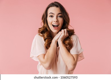 Portrait of an excited young girl in dress looking at camera isolated over pink background - Shutterstock ID 1060527593