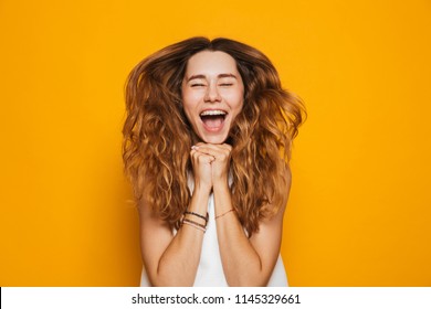 Portrait of an excited young girl screaming isolated over yellow background