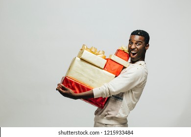 Portrait of an excited young man carrying many gifts , isolated on white studio background