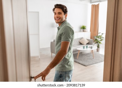 Portrait of excited young man walking in his apartment, entering new home and looking back at camera, happy young guy standing in doorway of modern flat, coming inside, selective focus