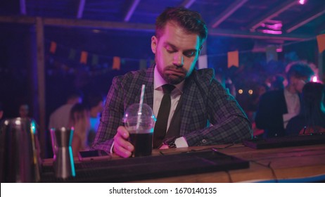 Portrait of exhausted businessman relaxing after hard working day drinking alcohol cocktail at bar counter in modern nightclub. - Shutterstock ID 1670140135