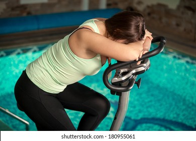 Portrait of exhausted woman spinning pedals on exercise bike