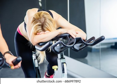 Portrait Of Exhausted Woman Spinning Pedals On Exercise Bike