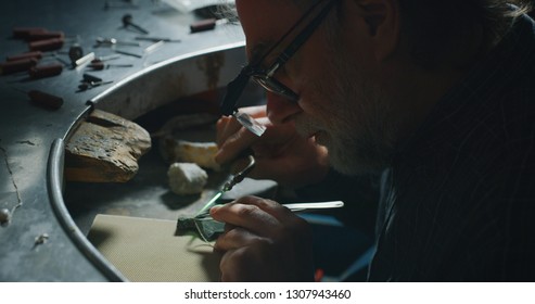 Portrait of experienced goldsmith working on a handmade jewelry bracelet chain of precious metal white gold in a workshop. Concept of jewelry, luxury, goldsmith, gold, silver, precious metals