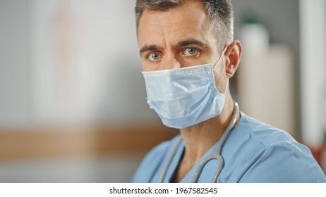 Portrait Of Experienced Male Nurse Wearing Blue Uniform And Face Mask At Doctor's Office. Medical Health Care Professional Working On Battling Stereotypes To Gender Diversity In Nursing Career.