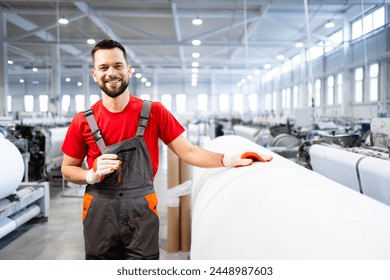 Portrait of experienced worker standing by machine and checking carpet production inside textile factory. - Powered by Shutterstock