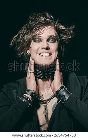 Portrait of an expressive young guy - a rock musician in the spotlight. Black background. Modern rock and punk culture.