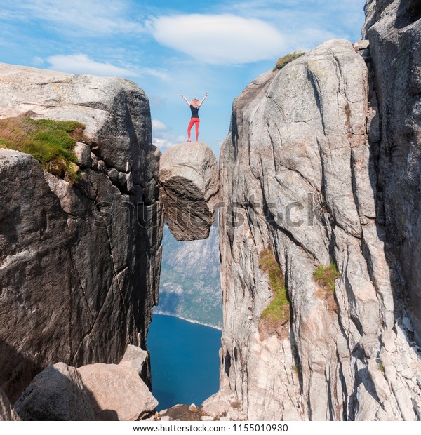 Portrait of a extreme plan travel for the girl\
on the stone of the kjerag in the mountains kjeragbolten of Norway,\
the feeling of complete freedom\
