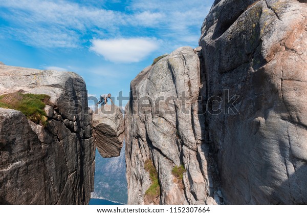 Portrait of a extreme plan travel for\
the handsome old man on the stone of the kjerag in the mountains\
kjeragbolten of Norway, the feeling of complete freedom\
