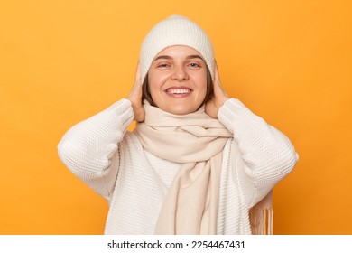Portrait of extremely happy overjoyed cheerful woman wearing warm jumper, hat and scarf posing isolated over yellow background, looking at camera with toothy smile, looks delighted. - Shutterstock ID 2254467431