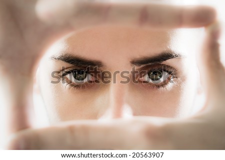 Portrait of eyes looking through fingers frame