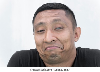 A Portrait Of The Face Of An Asian Indonesian Male Model Who Smiles And Frown Awkwardly At The Same Time AKA Frown Smile. Portrait On White Background.