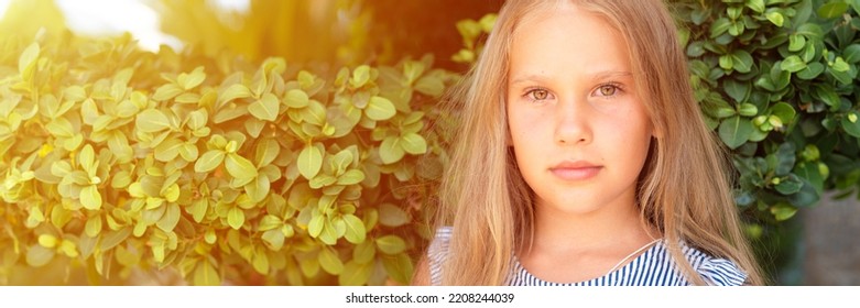 portrait face of candid happy little kid girl of eight years old with long blond hair on background of green plants during a summer vacation travel. gen z mental health concept. banner. flare - Shutterstock ID 2208244039