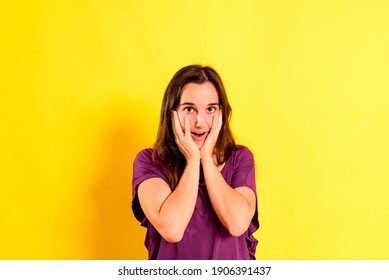 Portrait of the face of a young female student looking astonished at the results, isolated on yellow background.