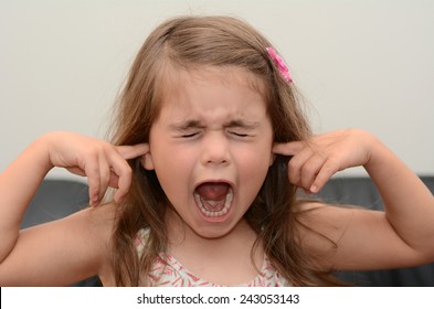 Portrait Face Of A Young Girl (female Age 05) With Closed Eyes And Covering Ears Screaming Very Loudly. Concept Photo Of Children Stress And Child Anxiety.Real People. Copy Space