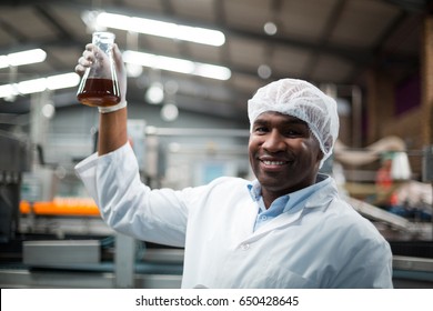 Portrait of factory engineers holding a sample of drink in drinks production plant - Powered by Shutterstock