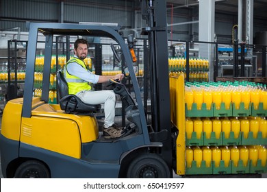 Portrait of factory worker loading packed juice bottles on forklift in factory - Powered by Shutterstock