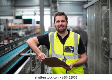 Portrait of factory worker standing with clipboard in factory - Powered by Shutterstock