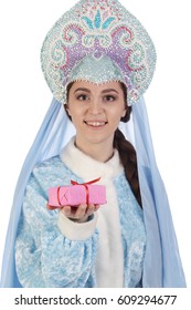 Portrait of a fairy-tale Snow Maiden in a blue suit and kokoshnik with a veil, gives a gift in a pink box
