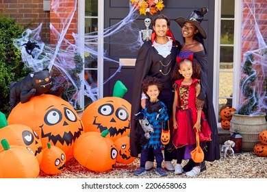 Portrait Of Family Dressed Up For Halloween Outside House Ready For Trick Or Treating