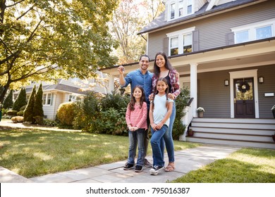 Portrait Of Family Holding Keys To New Home On Moving In Day