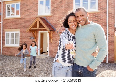 Portrait Of Family Holding Keys Standing Outside New Home On Moving Day