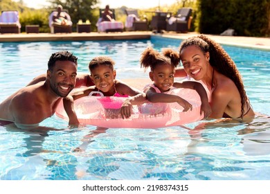 Portrait Family On Summer Holiday With Two Girls Floating In Swimming Pool On Inflatable Ring - Powered by Shutterstock