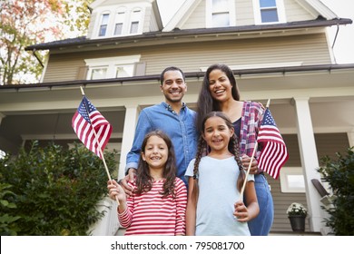 Portrait Of Family Outside House Holding American Flags