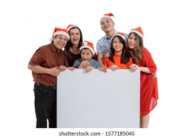 Portrait Of Family With Santa Claus Hat Smiling Holding Blank Board