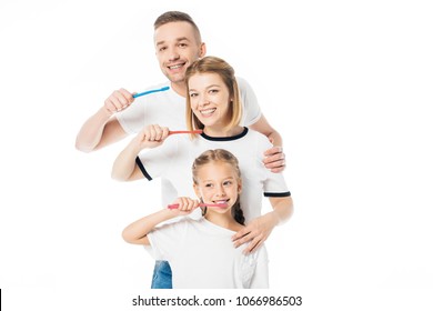 portrait of family in similar clothing with toothbrushes isolated on white