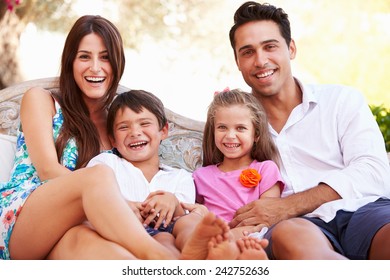 Portrait Of Family Sitting On Seat In Garden At Home - Shutterstock ID 242752636